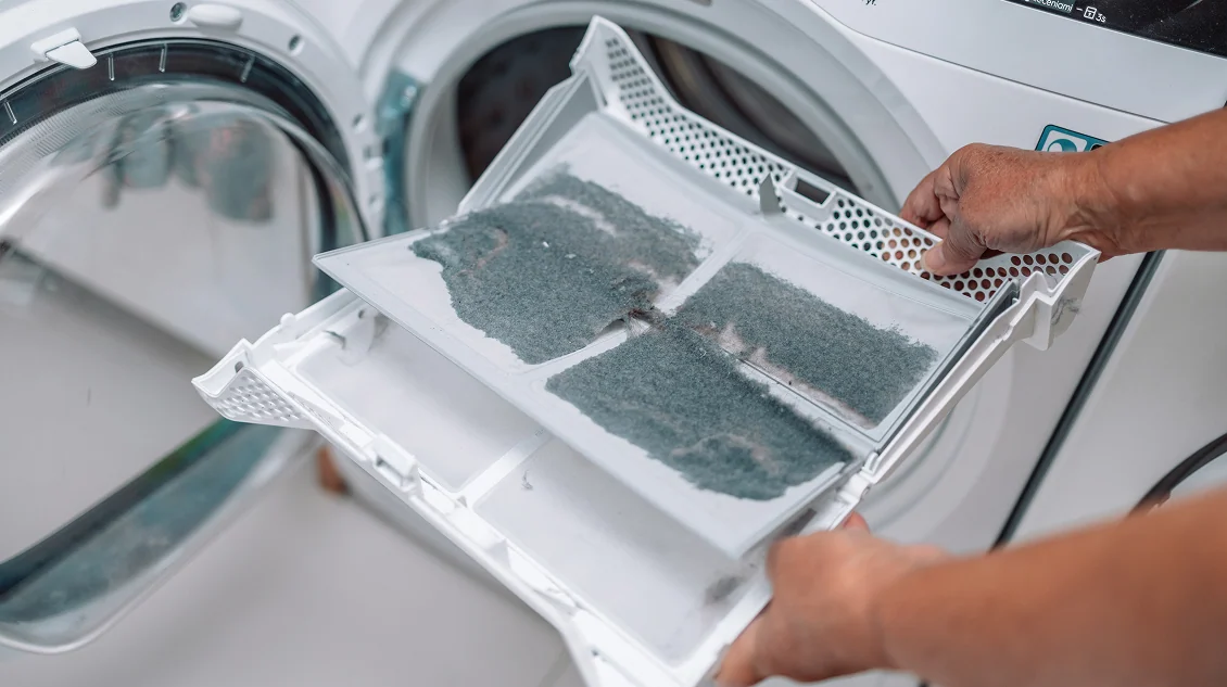 Technician removing lint from a clothes dryer filter during dryer vent cleaning