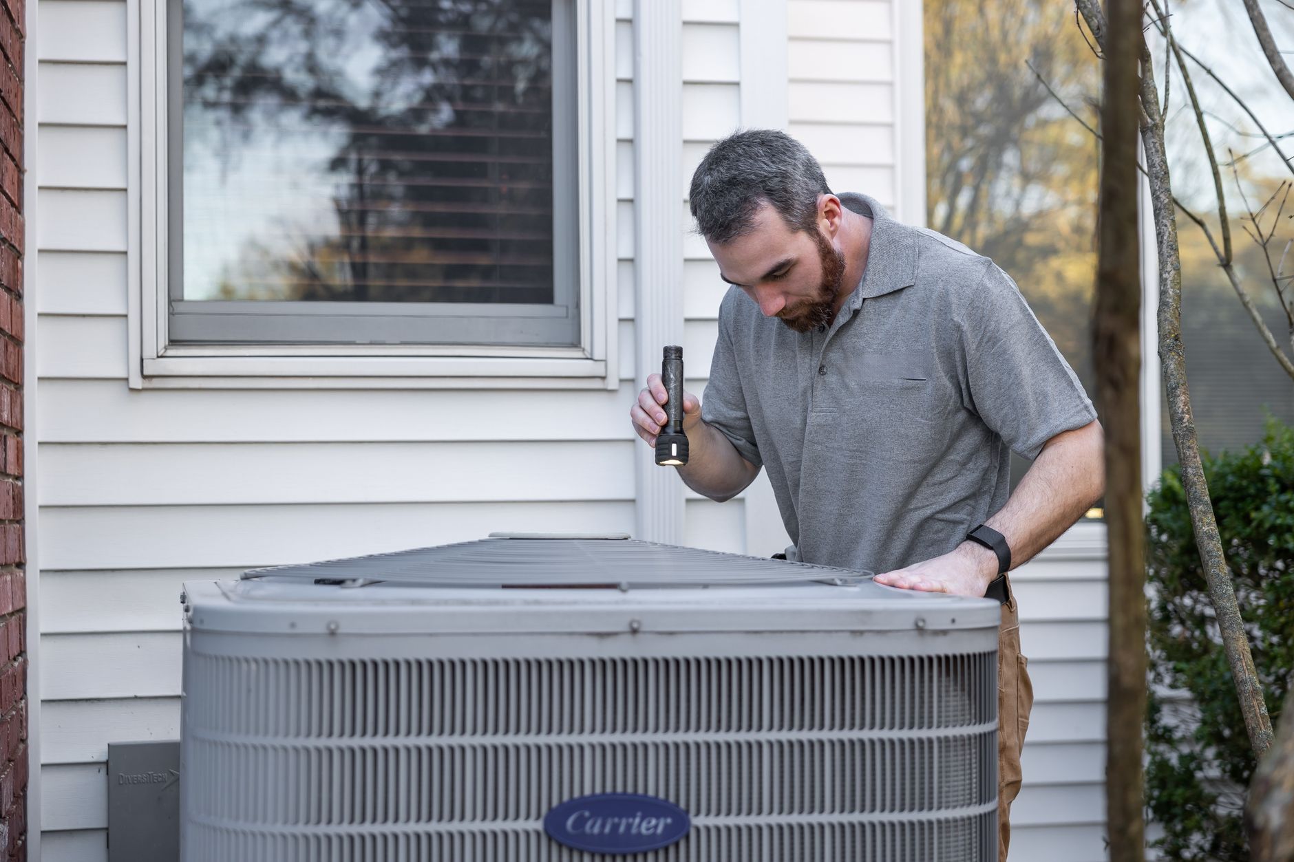 Technician inspecting an outdoor AC unit, a key item on a preventive maintenance checklist
