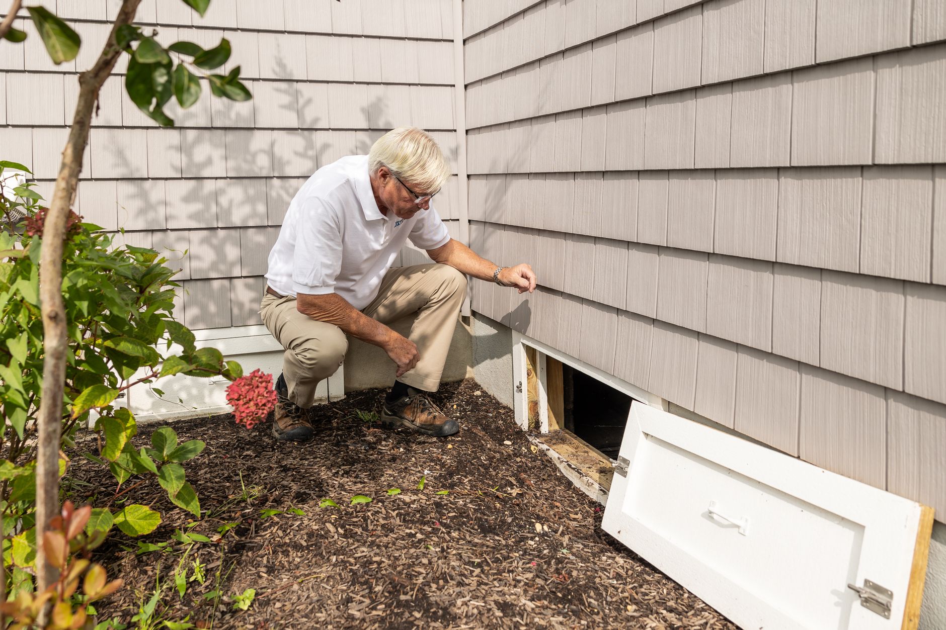 Technician inspecting a crawl space opening before crawl space cleaning
