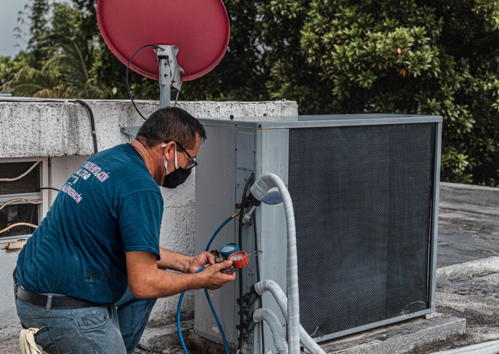 HVAC maintenance technician checking refrigerant pressure on a rooftop AC condenser