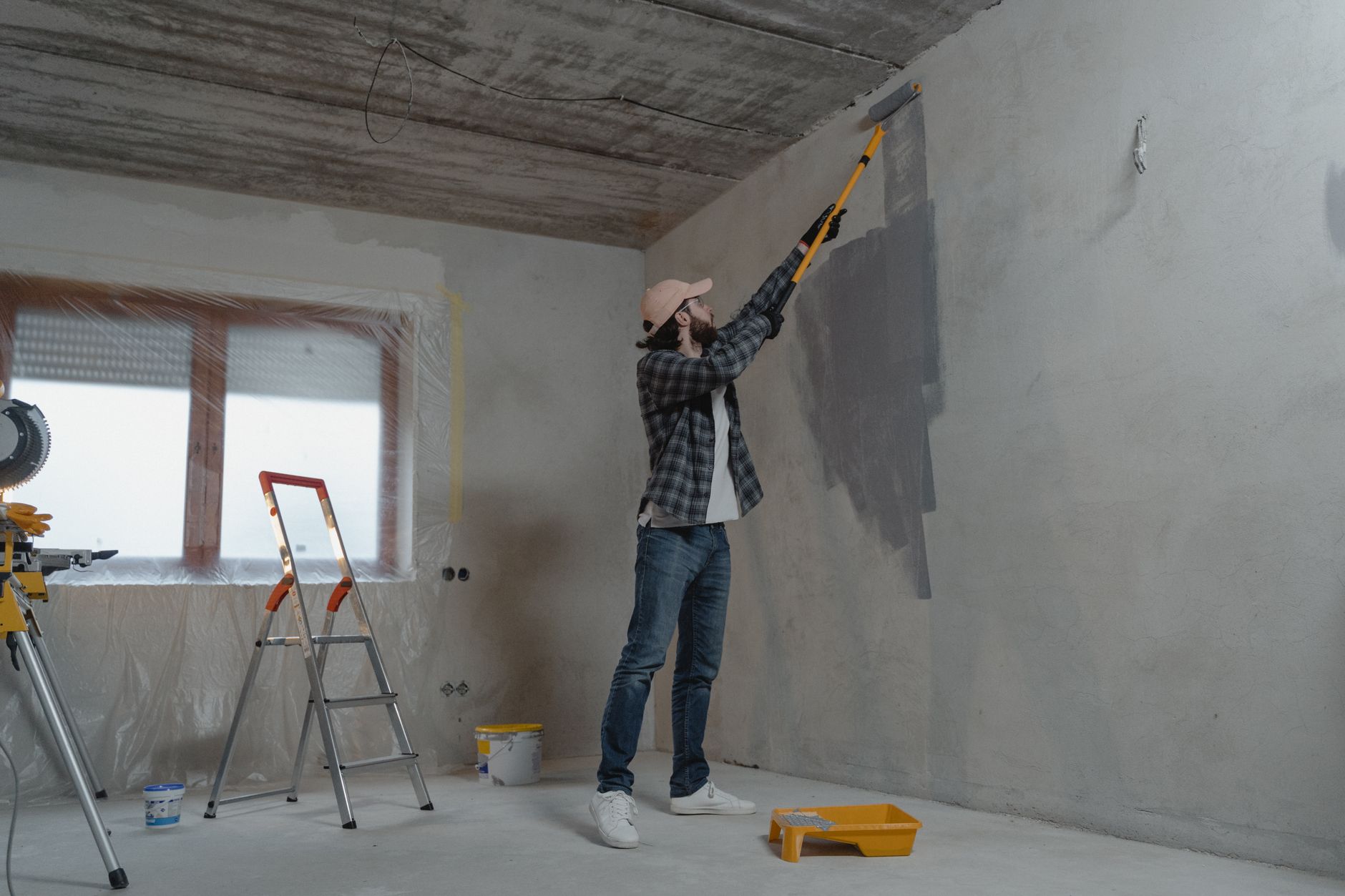Maintenance technician painting an apartment interior wall with a roller